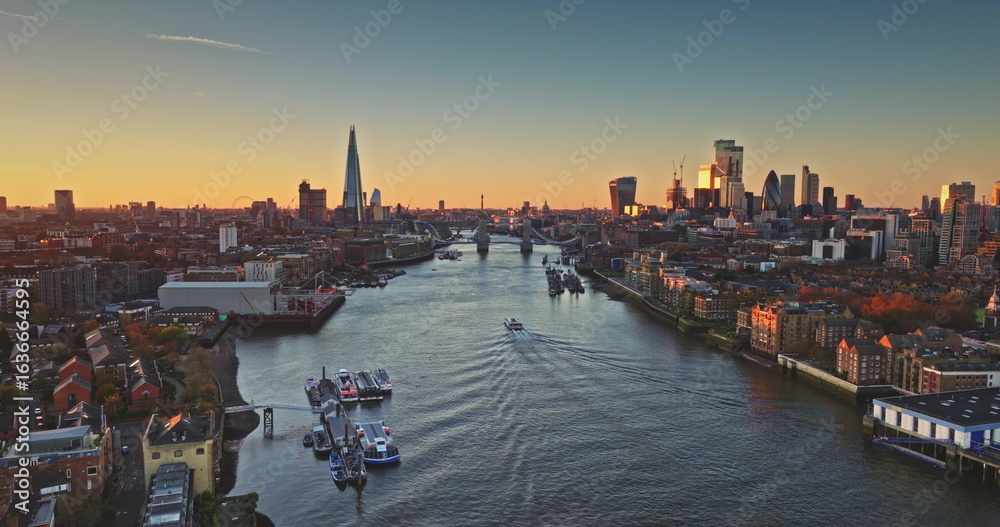 Fototapeta premium River Thames reflecting London cityscape at sunset, with The Shard and Tower Bridge standing out in the warm golden light, creating a breathtaking panorama of England's capital. Drone flight
