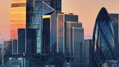 Photography United Kingdom, London: Modern glass skyscrapers reflecting sunset light during golden hour in London's financial district, creating a stunning cityscape
