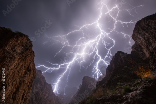 Fototapeta Naklejka Na Ścianę i Meble -  Intense lightning storm over canyon with jagged cliffs and dark sky.