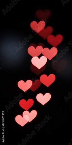 Red and pink heart-shaped bokeh lights on black background