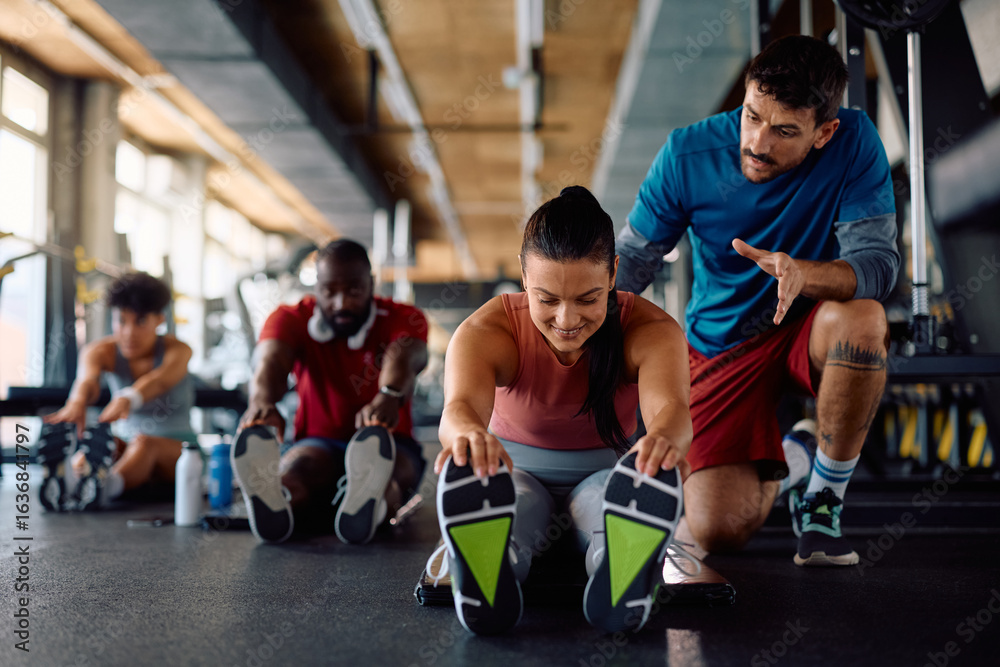 Fototapeta premium Happy sportswoman working out with help of coach during workout class in gym.