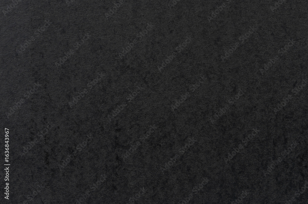 Fototapeta premium Dark texture resembling fabric or stone covering flat surface in soft lighting