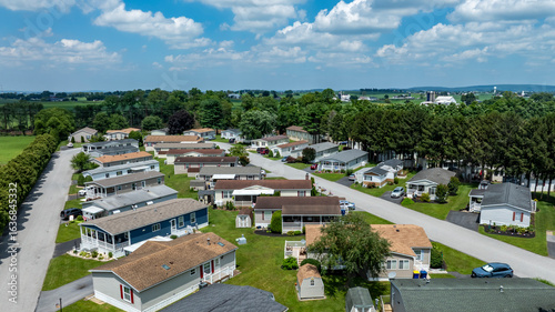 Obraz na plátně A peaceful community features rows of mobile homes surrounded by lush greenery under a bright blue sky