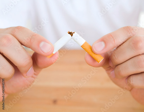 Breaking Free: A person snaps a cigarette in half, symbolizing the determination to quit smoking and embrace a smoke-free life. A powerful visual representation of health, recovery.