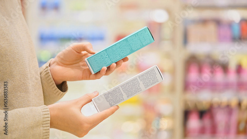 Woman selecting a cosmetic serum for face or hair in a beauty store, reading ingredients, comparing products. Female customer holding skincare or haircare item. Concept of conscious choice, self-care.