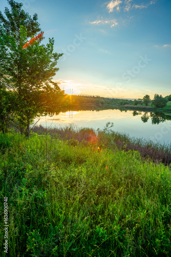Fotografie A quiet sunset on a calm lake, with the warm golden light reflecting on the wate
