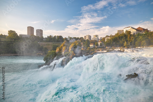 Majestic Rhine Falls cascading through lush greenery at sunset near Schaffhausen
