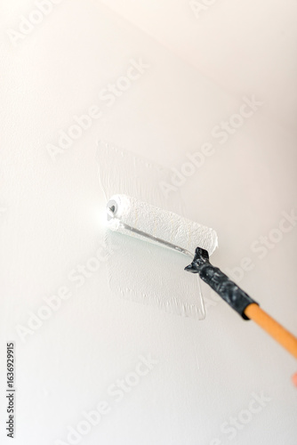 Painter applying white paint on wall with roller