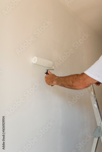 Painter using paint roller painting wall white