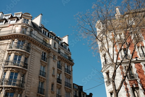 Charming Parisian Architecture with Sunlit Facades Against a Clear Blue Sky in an Urban Setting