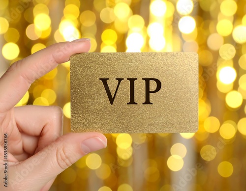 Hand holding a gold VIP card against a blurred golden background