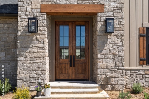 Entrance to a modern stone house featuring wooden double doors and decorative lanterns in a suburban neighborhood during daytime