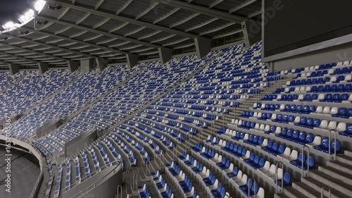 Aerial view drone flies over empty stadium or race track seats. Rows and blue and white seats without viewers and spectators. Evening shot of empty football stadium. Soccer Arena drone aerial view.