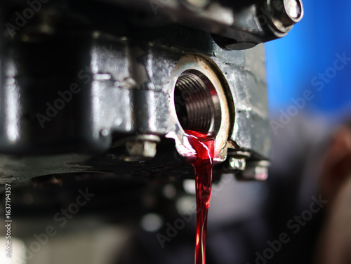 Auto mechanic loosen automatic transmission oil drain plug ,then let the old used automatic transmission oil flow out of the transmission oil pan.