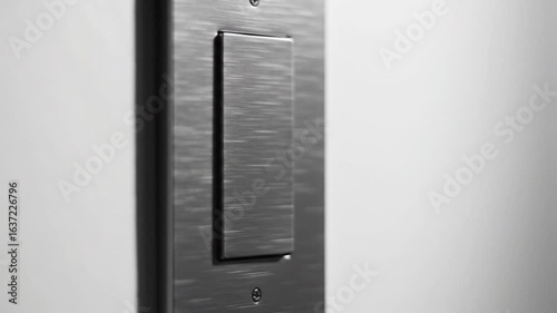Close up of a dark metal object with a rectangular cutout against a light gray background