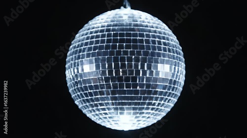 Classic silver mirrored disco ball spinning and glittering with bright light reflections against a pure black background perfect for party dance and music video
