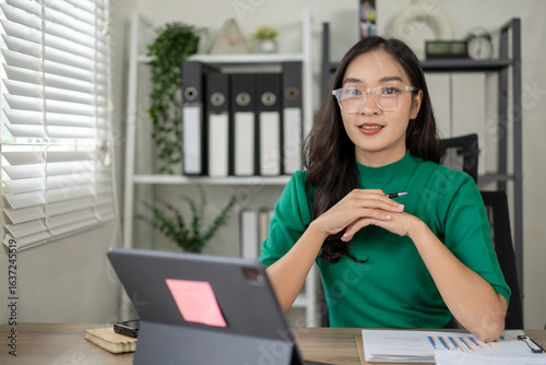 Εκτύπωση καμβά A woman in a green shirt sits at a desk with a computer and a tablet