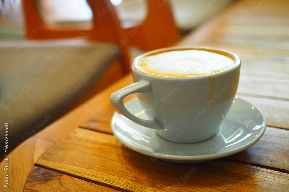 Fototapeta premium Cup of coffee on wooden table in cozy cafe setting