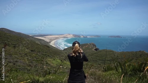 A woman with hat taking pictures at Cape Reinga in New Zealand.
