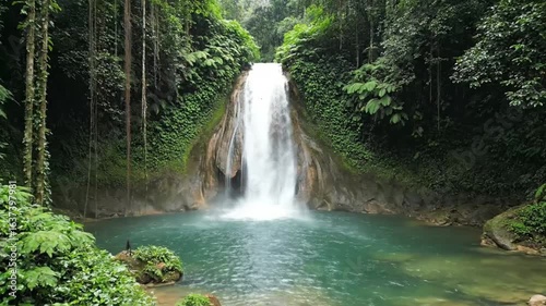 Lush rainforest waterfall cascades into a vibrant turquoise pool.