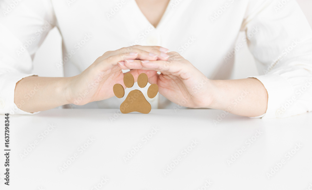 Obraz premium Hands Protecting Wooden Paw Print Symbolizing Pet Care, Safety and Animal Welfare