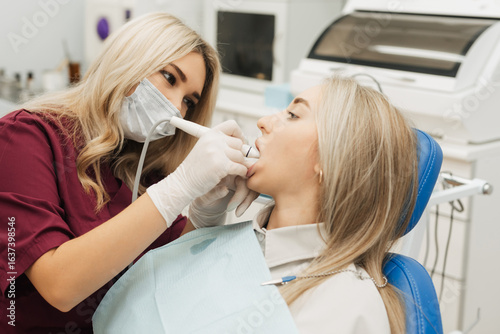 Fotografi The dentist begins a routine operation to clean the tartar of the female mouth