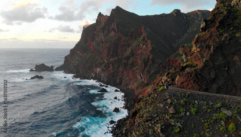 Obraz premium Traveler walking along a cliffside path overlooking the ocean, dramatic waves crashing below