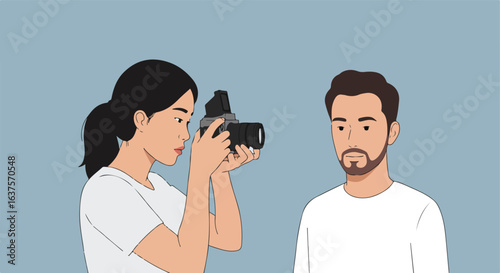 Woman takes picture of bearded man with camera against muted blue background