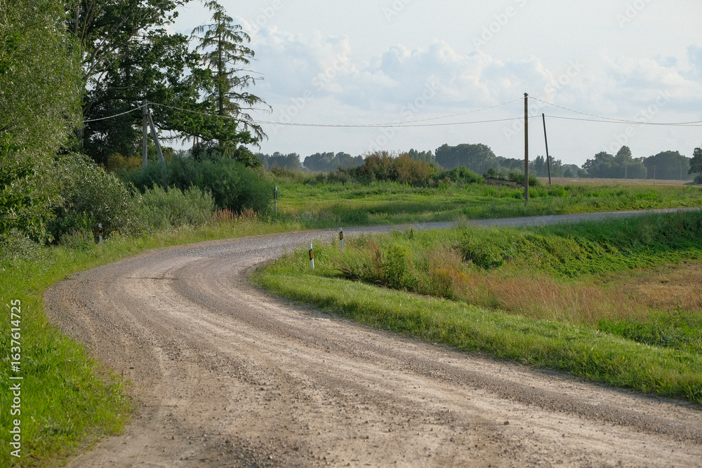 Naklejka premium winding gravel road in Latvia countryside in summer