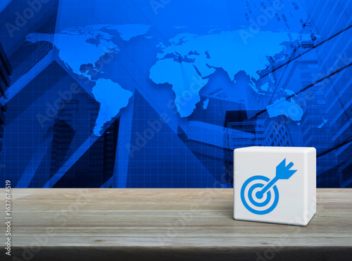 Fototapeta Naklejka Na Ścianę i Meble -  Target with dart flat icon on white block cube on wooden table over world map, modern office city tower and skyscraper, Business success concept, Elements of this image furnished by NASA