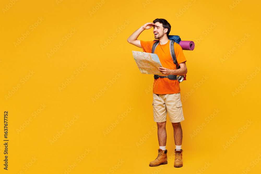Full body young fun traveler man carry backpack with stuff mat read paper map isolated on plain yellow background Tourist lead active lifestyle walk on spare time Hiking trek rest travel trip concept Full body young fun traveler man carry backpack with stuff mat read paper map isolated on plain yellow background Tourist lead active lifestyle walk on spare time Hiking trek rest travel trip concept