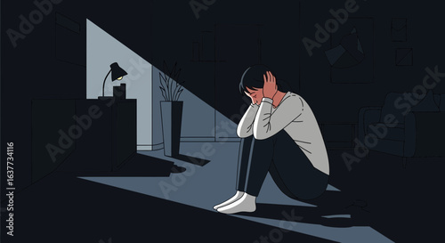 A person sits alone in a darkened room, head in hands, showing distress.
