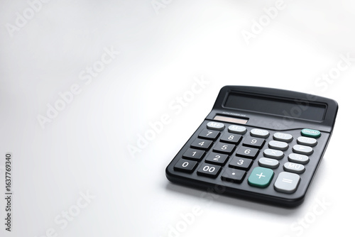 A black calculator with large buttons is placed on a white surface.