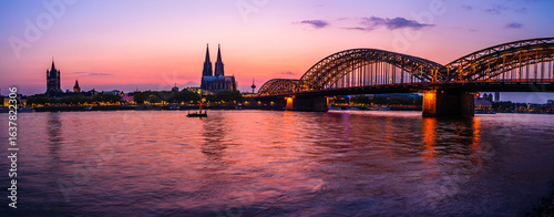 Evening silhouette skyline landscape of the gothic Cologne Cathedral, Hohenzollern railway and bridge, the old town and Great St Martin church in Cologne, Germany after sunset into blue hour