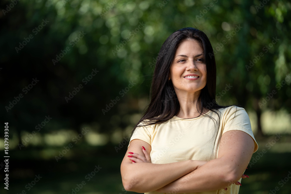 Portrait of smiling beautiful fit woman with crossed arms standing outdoors in park in morning Portrait of smiling beautiful fit woman with crossed arms standing outdoors in park in morning