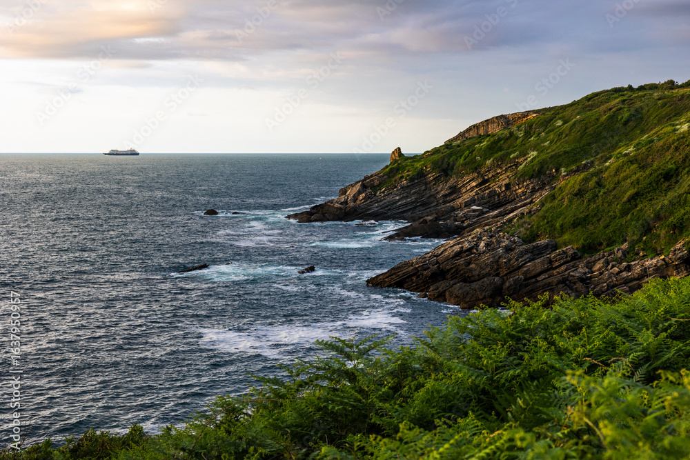 Obraz premium Rocky Coastline Under Cloudy Skies at the Foot of Mount Jaizkibel Around Cape Higuer