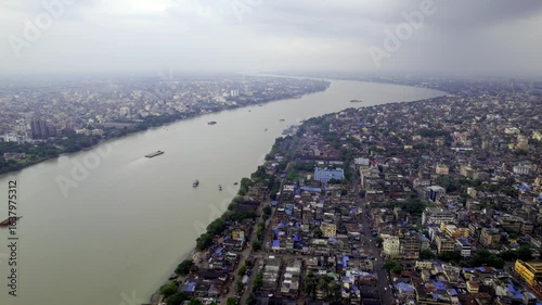 A drone aerial shot of the Kolkata or Calcutta city skyline, with a view of the holy Ganges or Hooghly river passing through the urban landscape of the historic city of Kolkata. 