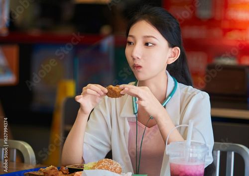 A cute Chinese girl enjoying a hearty meal at a fast-food restaurant in a shopping mall.