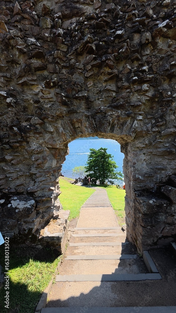 Obraz premium Natural landscape of the sea seen through a large wall opening, showing blue sky, greenery, and serene ocean view.