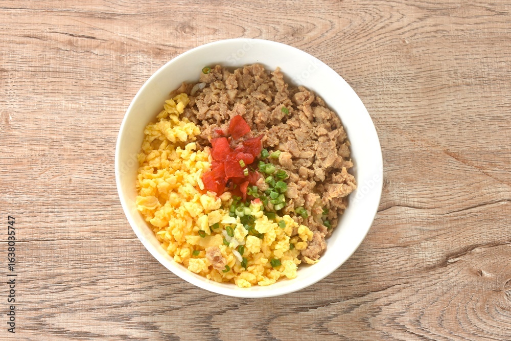 fried chop chicken and sweet egg toppiing red pickled cucumber on rice or tori soboro don japanese food in bowl fried chop chicken and sweet egg toppiing red pickled cucumber on rice or tori soboro don japanese food in bowl