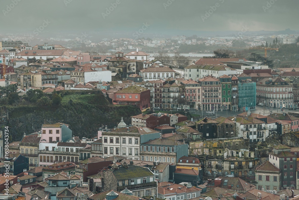Fototapeta premium A panoramic view unfolds, showcasing aged structures and quaint streets under a heavy, grey sky, as rooftops spread towards the distant horizon in Vila Nova de Gaia