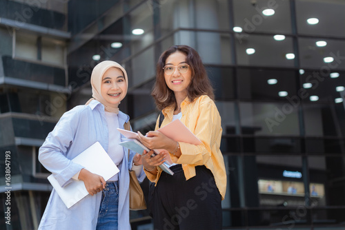 Canvas Print Two women are standing in front of a building, one of them is wearing a yellow shirt