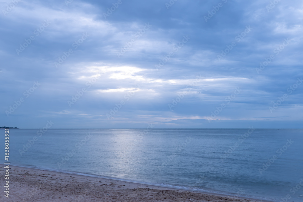 Fototapeta premium Serene ocean view at dawn with cloudy skies and gentle waves along the sandy beach
