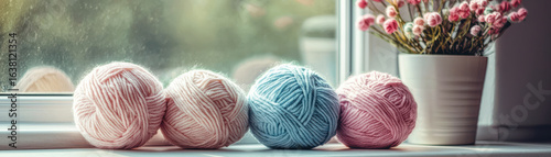 Pastel yarn balls and flowers on windowsill create cozy and serene atmosphere