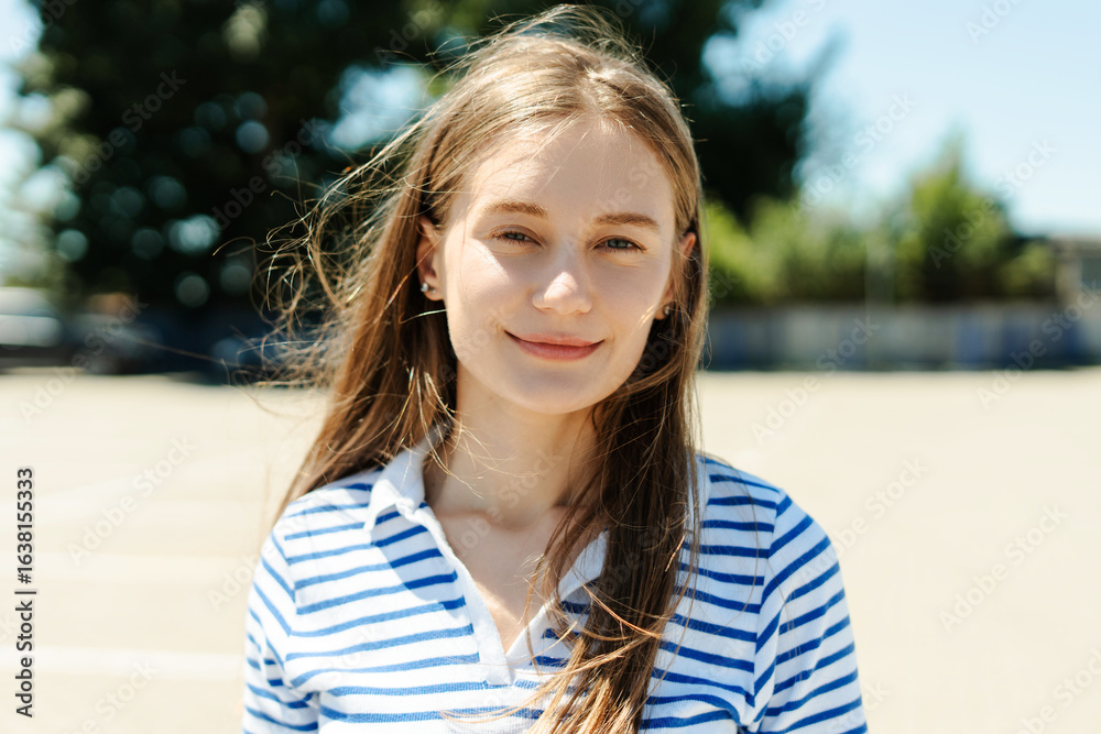 Portrait of smiling young woman with long brown hair wearing striped shirt outdoors Portrait of smiling young woman with long brown hair wearing striped shirt outdoors