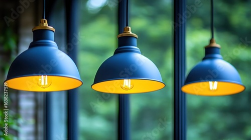 Three blue pendant lamps, yellow bulbs, window view