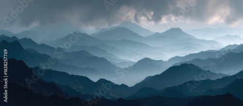 Misty, layered mountains under a brooding sky, shades of blue and grey dominate the scene, creating a serene yet powerful landscape