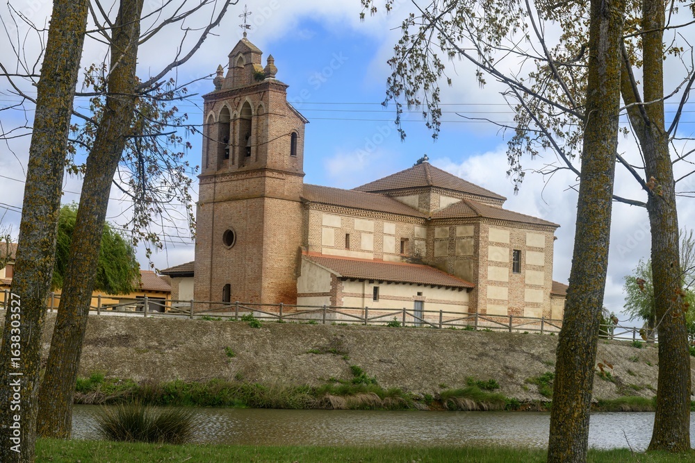 Fototapeta premium Church of San Pelayo in Villarrabe, Palencia, beside the river under cloudy sky