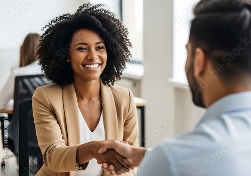 Smiling woman shakes hands with man in office setting