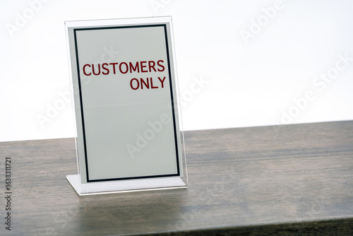 Fotografía Customers Only sign is displayed on wooden table, emphasizing exclusivity and access restriction